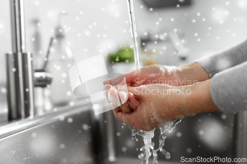 Image of woman washing hands with liquid soap in kitchen