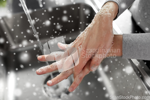 Image of woman washing hands with soap in kitchen