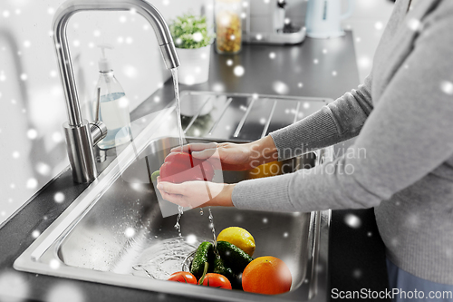 Image of woman washing fruits and vegetables in kitchen