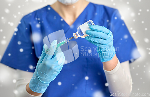 Image of doctor in face mask with syringe and medicine