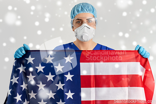 Image of doctor in goggles and mask holding flag of america