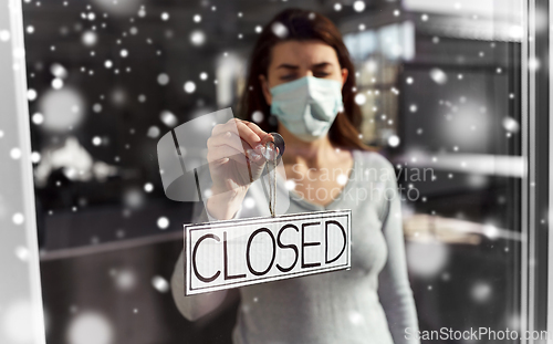 Image of woman in mask hanging banner closed on door