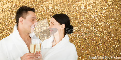 Image of happy couple in spa bath robes drinking champagne