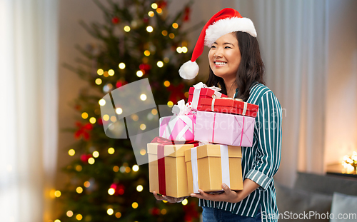 Image of happy asian woman with christmas gifts at home