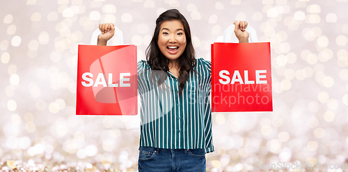 Image of happy asian woman with shopping bags over lights