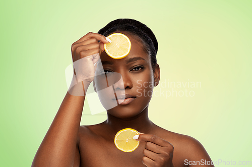 Image of african woman making eye mask of lemons