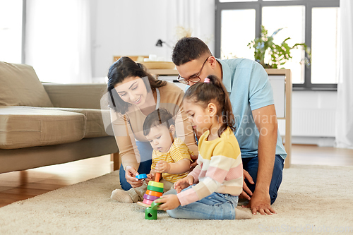 Image of happy family playing with pyramid toy at home