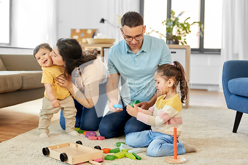 Image of happy family palying with wooden toys at home