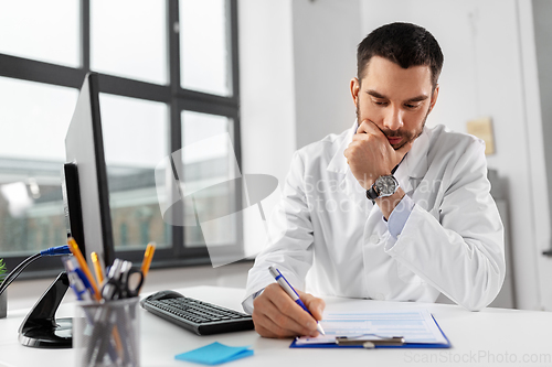 Image of stressed male doctor with clipboard at hospital