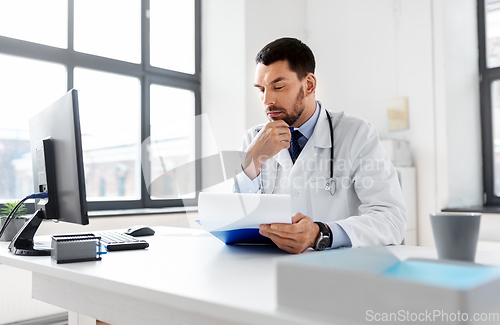 Image of stressed male doctor with clipboard at hospital