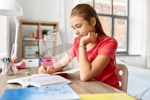 Image of student girl with book writing to notebook at home