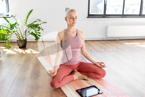 Image of woman with tablet pc meditating at yoga studio