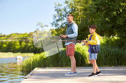 Image of happy smiling father and son fishing on river