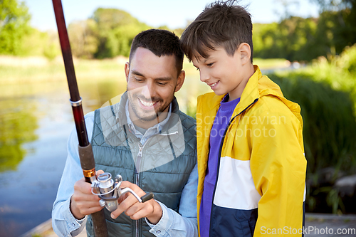 Image of happy smiling father and son fishing on river