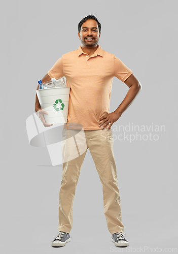 Image of smiling young indian man sorting plastic waste