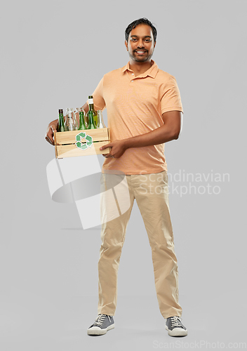 Image of smiling young indian man sorting glass waste