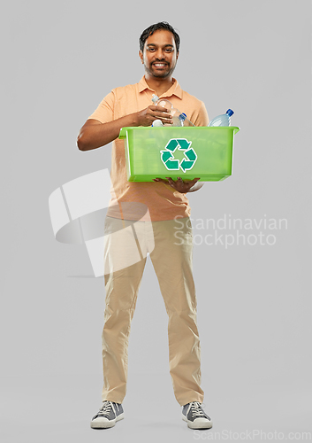 Image of smiling young indian man sorting plastic waste