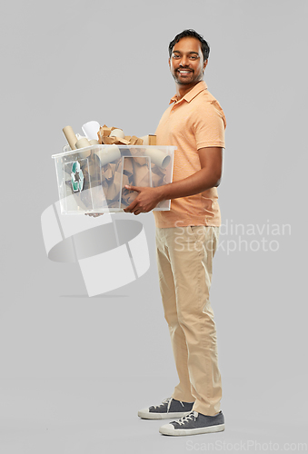 Image of smiling young indian man sorting paper waste