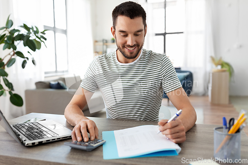 Image of man with files and calculator works at home office