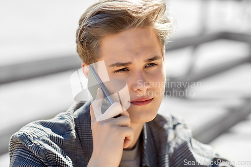 Image of teenage boy calling on smartphone outdoors