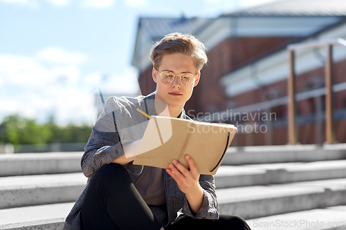 Image of young man with notebook or sketchbook in city