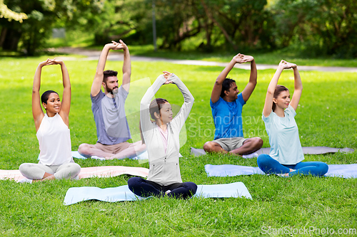 Image of group of happy people doing yoga at summer park