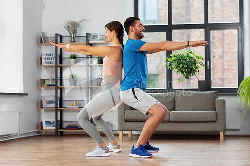 Image of happy couple exercising and doing squats at home