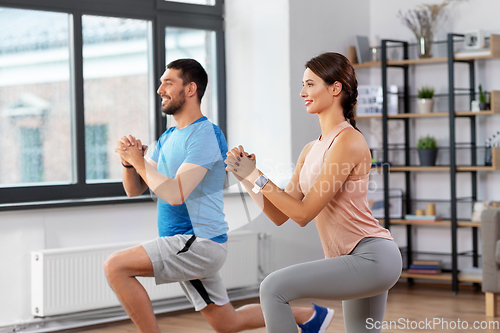 Image of happy couple exercising and doing squats at home