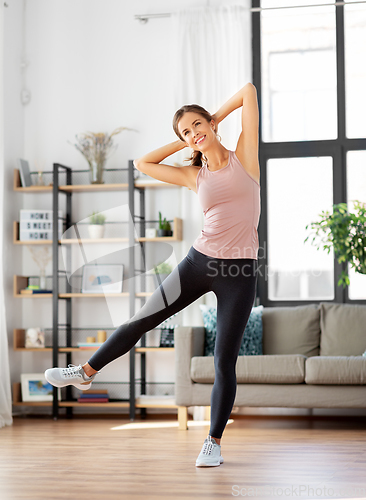 Image of smiling young woman exercising at home