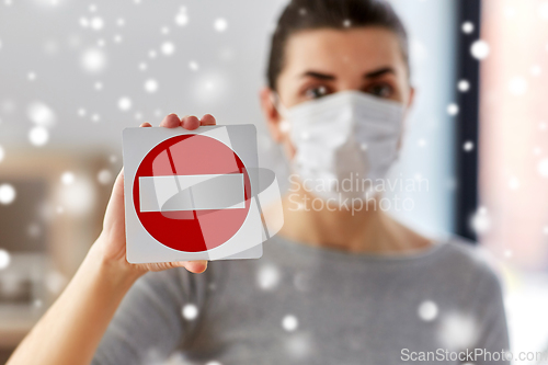 Image of woman in protective medical mask showing stop sign