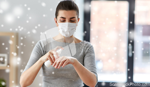 Image of close up of woman in mask spraying hand sanitizer