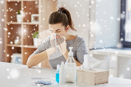 Image of sick woman with medicine blowing nose to wipe