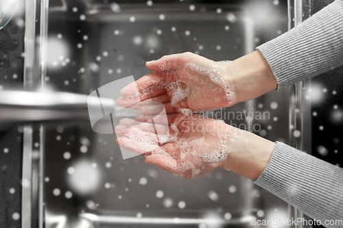 Image of woman washing hands with soap in kitchen