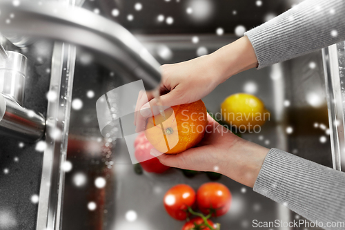 Image of woman washing fruits and vegetables in kitchen