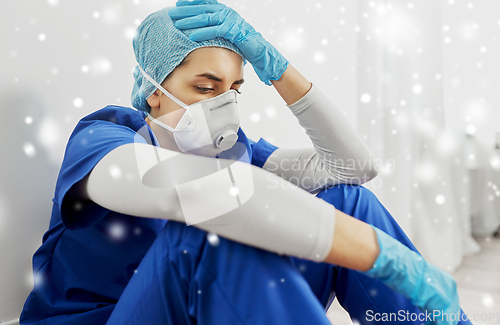 Image of sad doctor or nurse in face mask holding to head