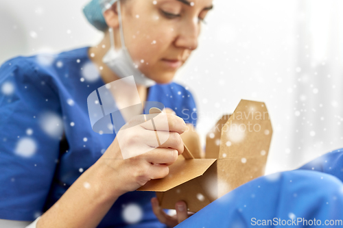 Image of sad doctor or nurse eating takeaway food from box