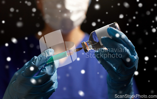 Image of doctor in face mask with syringe and medicine