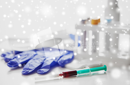 Image of close up of blood in syringe, gloves and mask