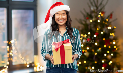 Image of happy asian woman with christmas gift at home