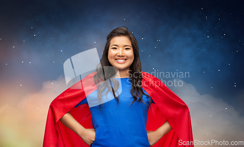 Image of happy asian woman in red superhero cape at night
