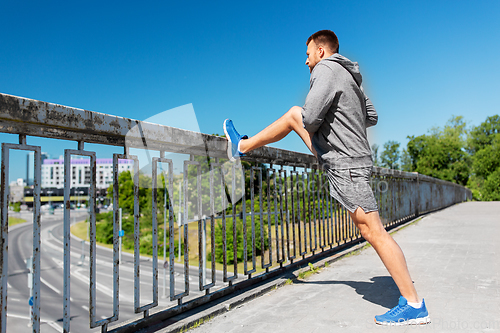 Image of man stretching leg on bridge