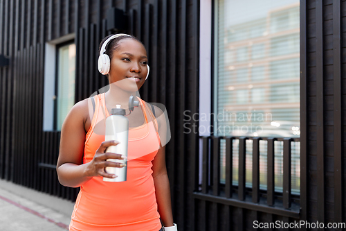 Image of african american woman drinking water after sports