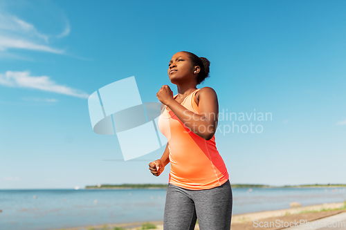 Image of young african american woman running at seaside