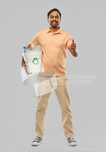 Image of smiling young indian man sorting plastic waste