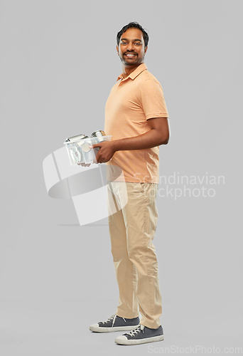 Image of smiling young indian man sorting metallic waste