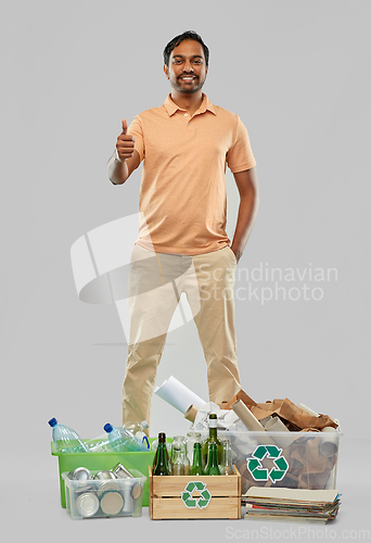 Image of smiling man sorting paper, glass and plastic waste