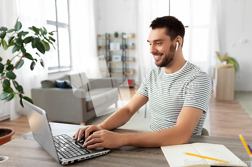 Image of man with laptop and earphones at home office