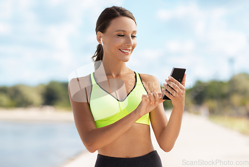 Image of woman with earphones and smartphone doing sports