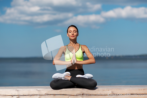 Image of young woman meditating in lotus pose at seaside