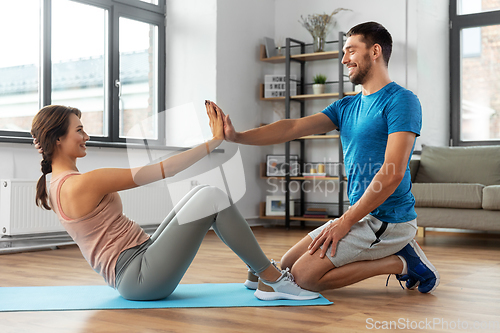 Image of woman with personal trainer doing sit ups at home